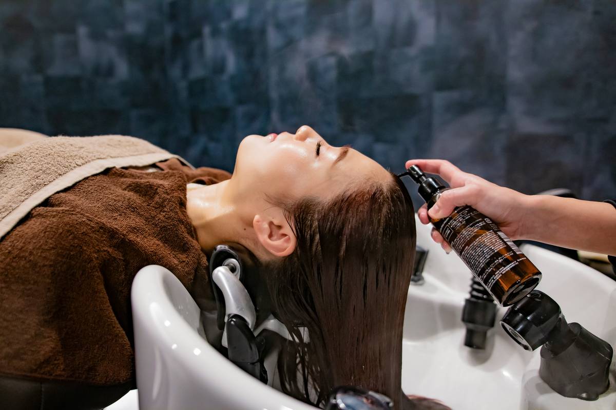 Woman applying keratin treatment to curly hair in salon setting